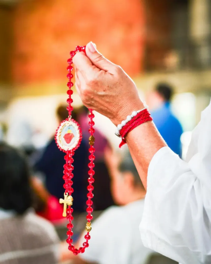 Una mano alza el rosario en la procesión